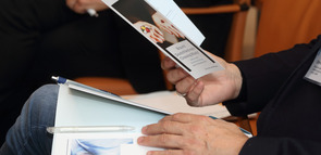 Konferenzteilnehmer hält Programm in den Händen