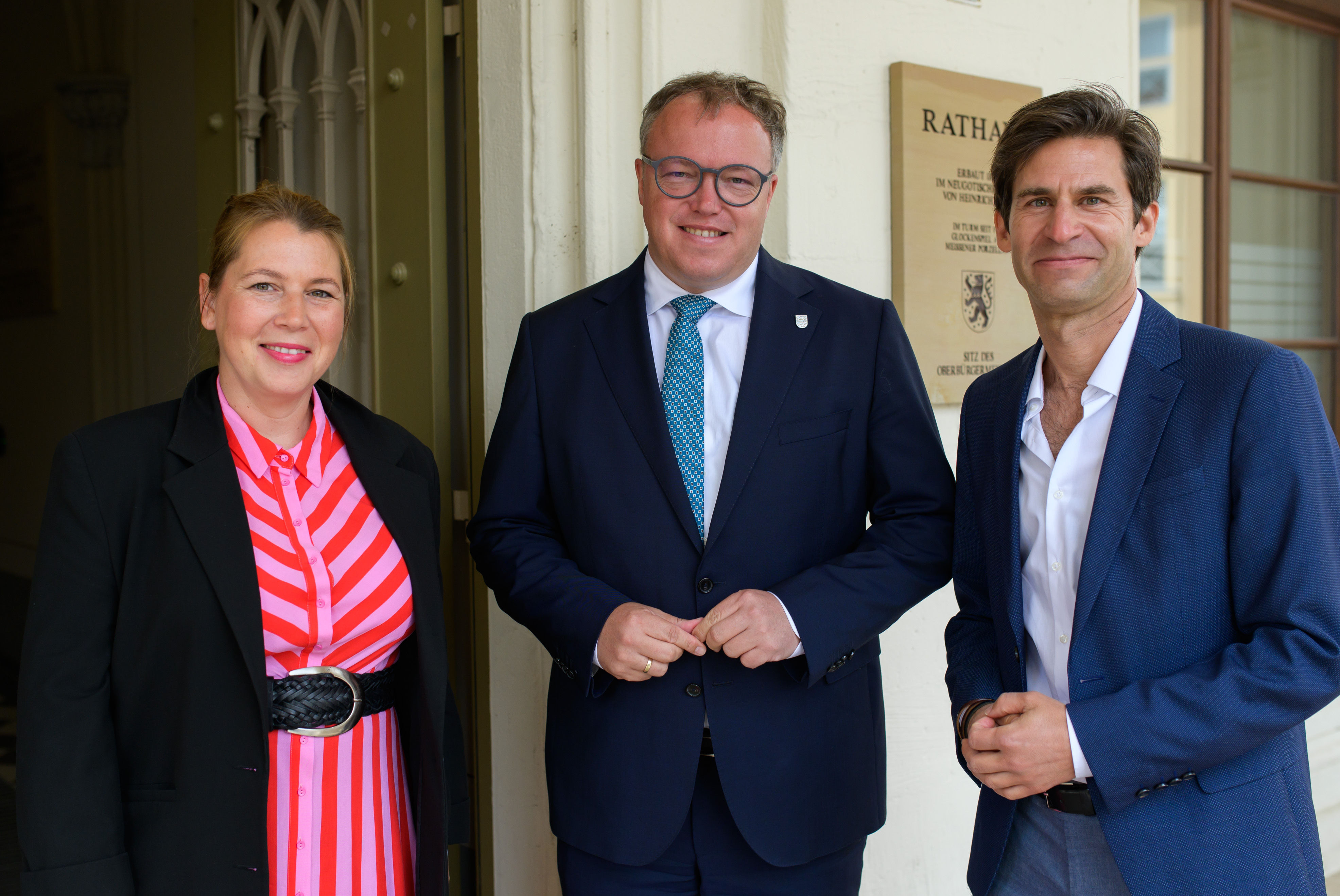 Drei Personen vor Rathaus